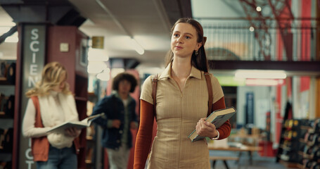 Book, ideas and woman student in library with planning for studying with university exam at campus. Friends, walking and person brainstorming with literature for college test, project or assignment.