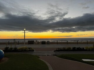 Early morning view of Virginia Beach boardwalk with benches and light pole under a dramatic sky