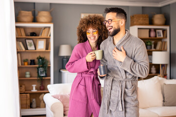 Happy Couple Relaxing in Bathrobes While Enjoying Coffee in a Bright and Cozy Living Room