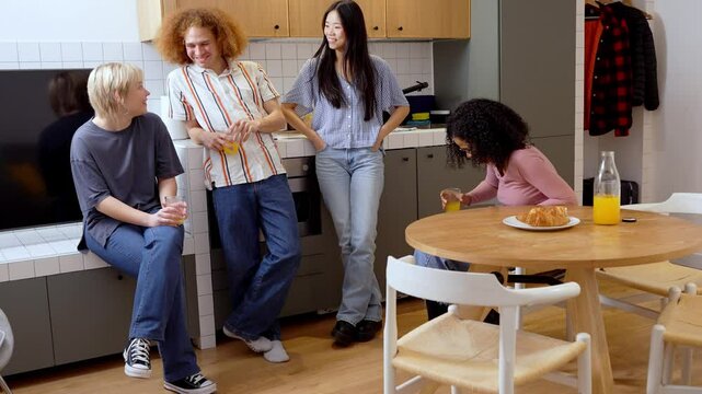 Multiethnic friends share breakfast and laughter in a modern kitchen, enjoying a casual morning together