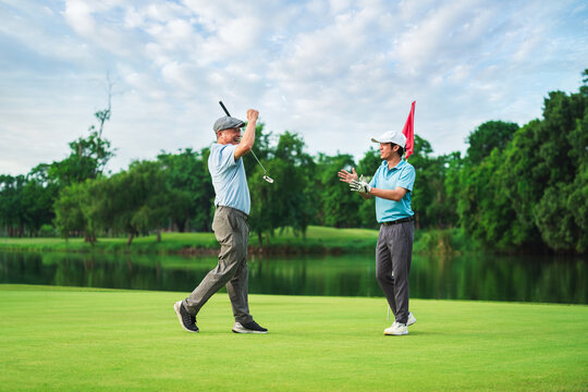 Senior Golfer and Young Player Celebrate Winning Moment on Green in Summer Golf Tournament for Family Bonding