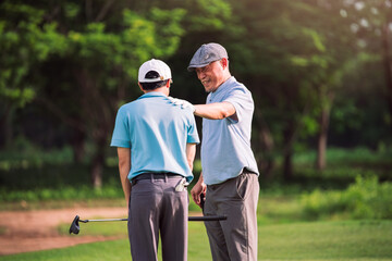 Senior Man Teaching Young Golfer on Green Lawn During Outdoor Golf Lesson for Family Bonding and...