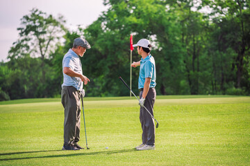 Senior Man Teaching Young Golfer on Green Lawn During Outdoor Golf Lesson for Family Bonding and...