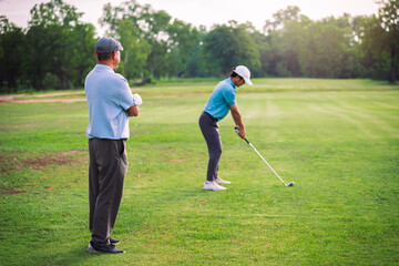 Senior Man Teaching Young Golfer on Green Lawn During Outdoor Golf Lesson for Family Bonding and Sport Education