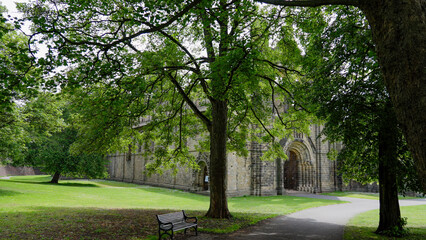 Scenic view of Kirkstall Abbey in Leeds, West Yorkshire, England, with a park bench in the foreground