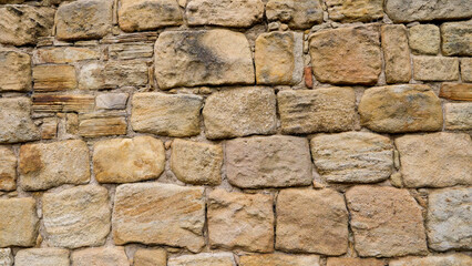 Weathered sandstone blocks forming an old wall, creating a textured background ideal for design projects