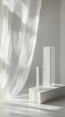 Sheer white curtain drapes over minimalist white geometric sculptures on a white platform, bathed in sunlight casting shadows