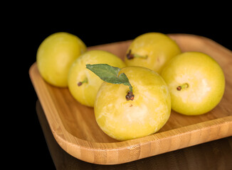 Yellow juicy plums isolated on black background, close-up.