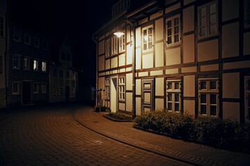 Peaceful night view of a half-timbered house illuminated by a single streetlamp on a quiet...
