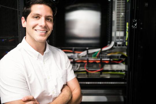 Man standing with arms crossed in server room beside server rack and network cables, copy space - Powered by Adobe