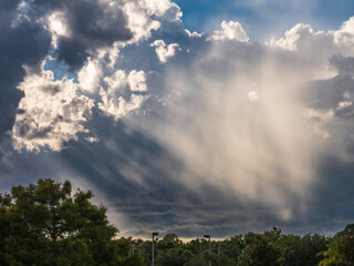 Saharan dust glows in sunlight slanting through gaps between bright and shadowy clouds on a June evening in southwest Florida, for motifs of seasonal weather and visually dramatic natural phenomena