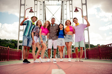 Diverse group of happy young friends enjoying a cheerful day outdoors on a city bridge during a...