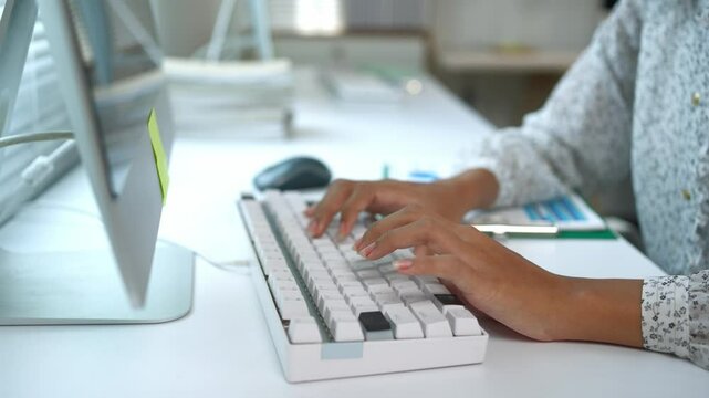 Female hands efficiently typing on white keyboard, showcasing professional workspace with focused data entry and digital communication