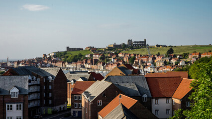 Red roofed houses and harbor with Whitby Abbey on the hill in North York Moors National Park, Whitby, UK