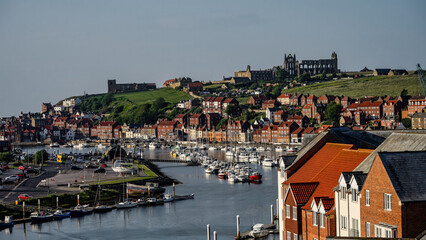 Scenic view of Whitby harbor in North Yorkshire, England, featuring numerous boats and the historic Whitby Abbey perched on the clifftop
