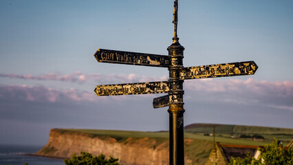 Old metallic signpost showing directions to different places in Saltburn by the Sea, UK