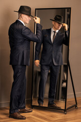 Elegant mature businessman in wardrobe stand in front of mirror and choose tie. Confident handsome...