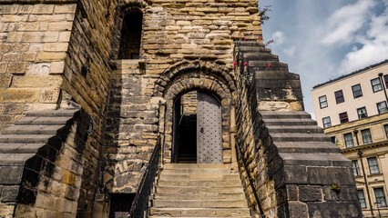 Stone stairs leading to a partially open wooden door in the Newcastle Castle keep, UK