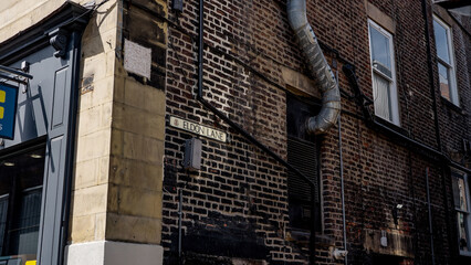Eldon Lane street sign in Newcastle city centre, showing brick wall, windows and ventilation pipe