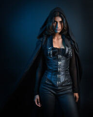  portrait of mysterious hooded woman in black cloak,  gothic fantasy or dystopian character. posing with gestural magical hand poses.  lit with moody shadows, studio scene on dark isolated background