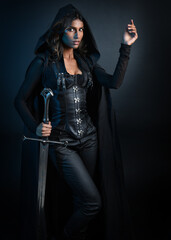 portrait of mysterious hooded woman in black cloak, gothic fantasy or dystopian character, holding sword weapon. lit with moody cinematic shadows, studio scene on dark isolated background