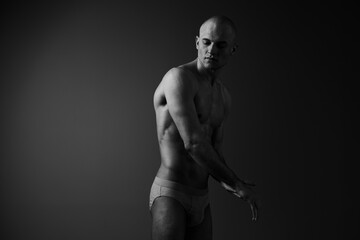 Naklejka premium Black and white image of a thoughtful man, showcasing elegance and strength through body language and posture, evoking a sense of introspection.