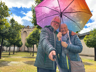 Smiling senior couple takes a selfie together in the garden of a historic house out of Seville during a sightseeing trip enjoying the culture and the pleasant retirement lifestyle