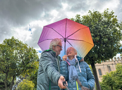 Smiling senior couple takes a selfie together in the garden of a historic house out of Seville during a sightseeing trip enjoying the culture and the pleasant retirement lifestyle
