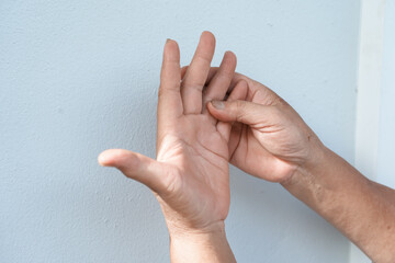 A woman uses her other hand to feel pain and tingling. along with Guillain-Barre syndrome and numbness in the hands Elderly woman tries to massage herself to relieve wrist pain