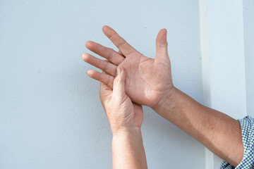 A woman uses her other hand to feel pain and tingling. along with Guillain-Barre syndrome and numbness in the hands Elderly woman tries to massage herself to relieve wrist pain