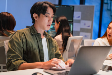 Asian programmers collaborating on software development at night, focused on writing code across multiple monitors in a tech office environment  Programmers Collaborating on Software Development 