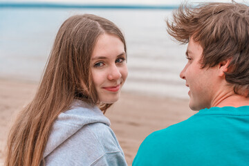 Obraz premium Happy couple in love sitting by the sea, a romantic date between a teenage boy and a girl