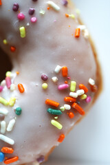 A close up of a white donut with sprinkles.