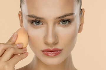Professional makeup application with beauty sponge, showcasing flawless skin and precise cosmetic technique