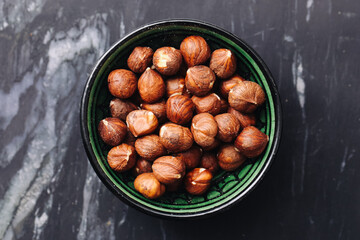 Hazelnuts in green bowl. Brown shelled nuts. Organic healthy snack. Vegan food texture. Closeup rustic flatlay.