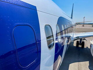 Close-up view of an airplane parked at the airport on a clear sunny day with blue skies