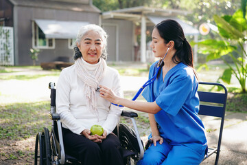 Fototapeta premium A woman in a wheelchair is being checked by a nurse