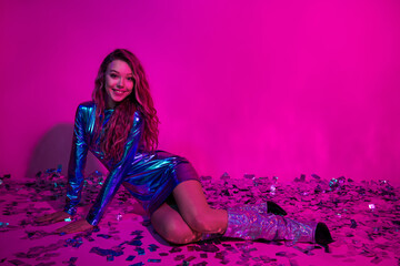 Stylish woman in a blue dress posing on a pink neon background, celebrating with confetti, advertising, fashion, or nightclub promotions