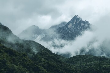 Misty mountain range shrouded in low-hanging clouds, verdant slopes and a prominent peak