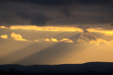 Dramatic golden sun rays breaking through dark clouds.