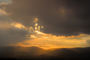 Obraz premium Dramatic sunset with sun rays breaking through clouds.