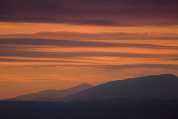 Vibrant orange and purple sunset stripes above mountains.