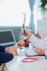 Fototapeta premium Female doctor gives advice and explanation to patient with dementia and stroke in examination room using human brain anatomy model and blood pressure measurement. Healthcare and medical concept. 