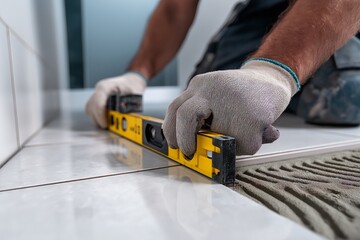 Worker tiling on wall, measuring tile flooring renovation process. Concept of worker tiling on wall, showcasing precision in modern home improvement project.
