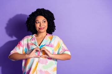 Joyful woman in vibrant shirt posing on a violet background expressing happiness