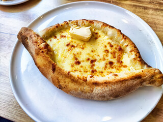 Cheese-filled bread dish served on a white plate in a cozy dining setting during a sunny afternoon