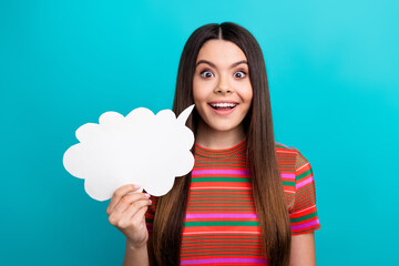 Excited young woman holding a blank speech bubble for advertising with a turquoise background...