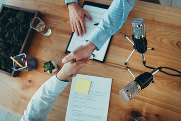Workplace handshake with microphones and documents symbolizing agreement, teamwork, and collaboration