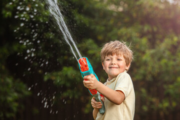 Happy child playing with water gun outdoors on a sunny day. Perfect summer activity, game, fun, and playful childhood concept. Great image for themes like outdoor fun, summer games, kids&rsquo; activities.
