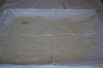 The first small round dough ball dusted with flour set on a white cloth surface with many more to...